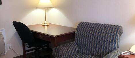 Une chambre d’hôtel équipée d’un bureau, d’une chaise, d’une lampe et d’un téléphone.