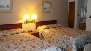 A hotel room with two beds, a nightstand with lamps, and framed pictures on the wall.