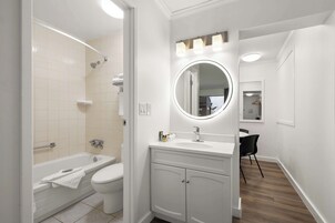Un baño moderno con bañera, inodoro, tocador con espejo y ducha.