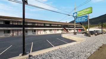 A motel with a sign advertising SureStay Hotel by Best Western, featuring amenities like free WiFi, a hot tub, and kitchen suites.
