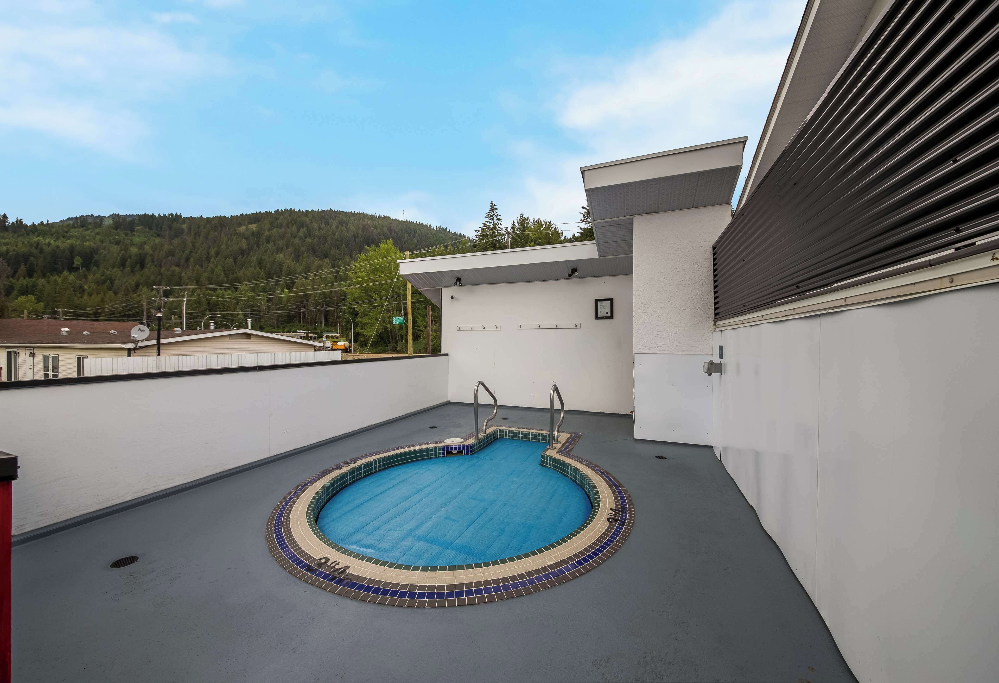 Una piscina en la azotea con interior azul, rodeada por un edificio blanco de diseño moderno.