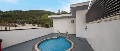 Una piscina en la azotea con interior azul, rodeada por un edificio blanco de diseño moderno.