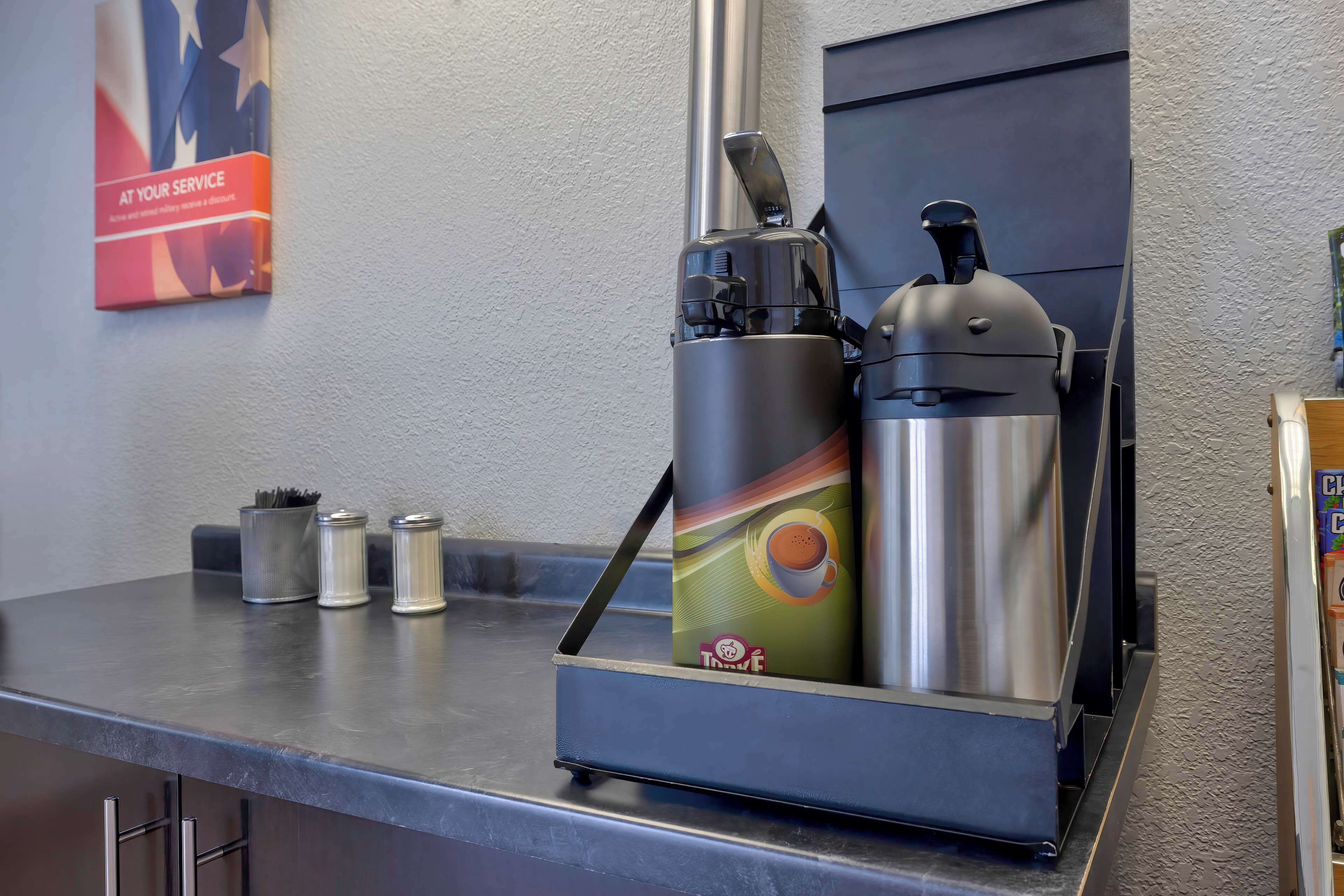 A coffee machine with a colorful design, a stainless steel container, and a metal pitcher on a countertop.