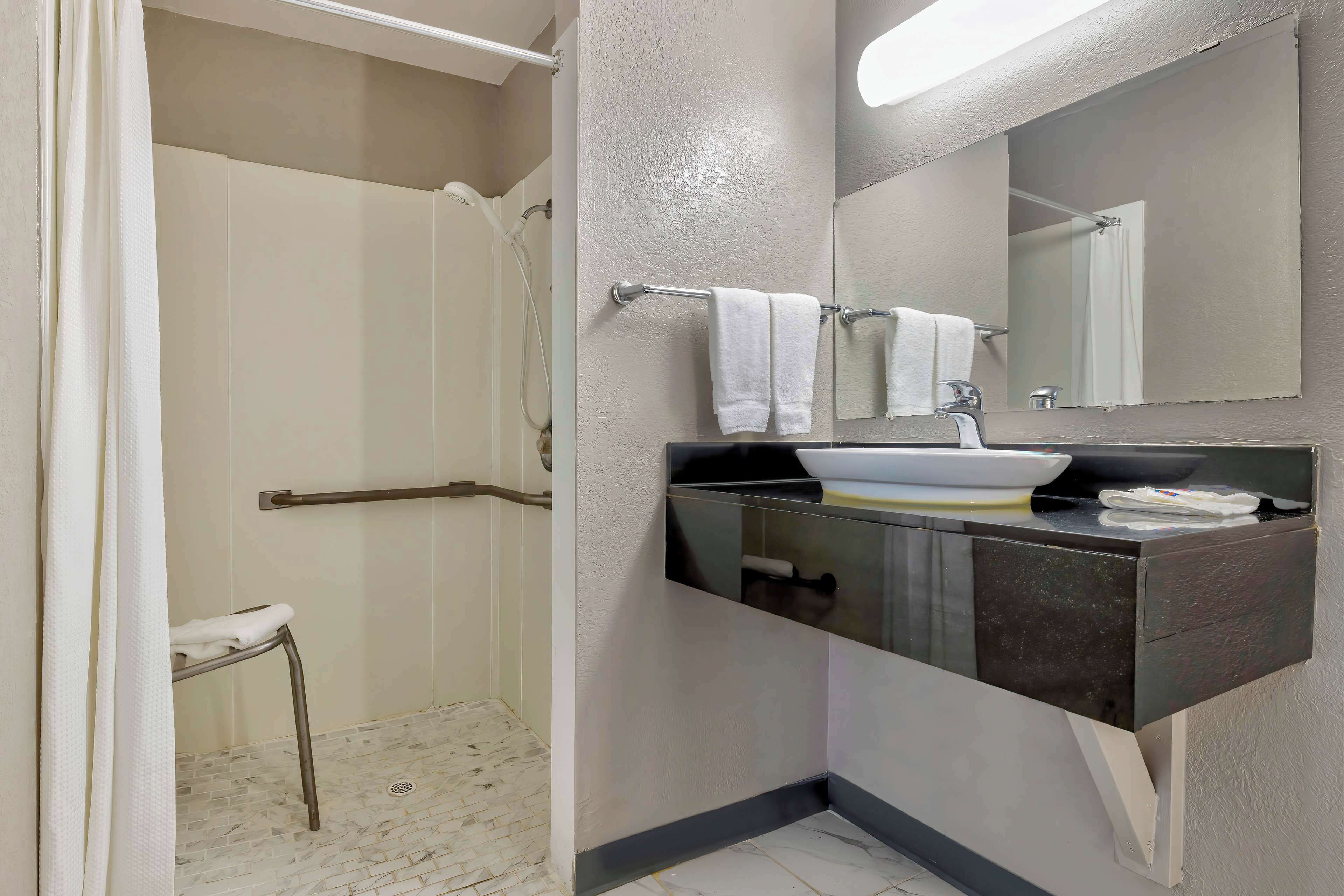 A bathroom with a shower, a sink with a mirror, and a towel rack.