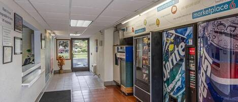Un couloir avec un comptoir d’accueil, un distributeur automatique et un panneau indiquant « espace commercial 6 ».