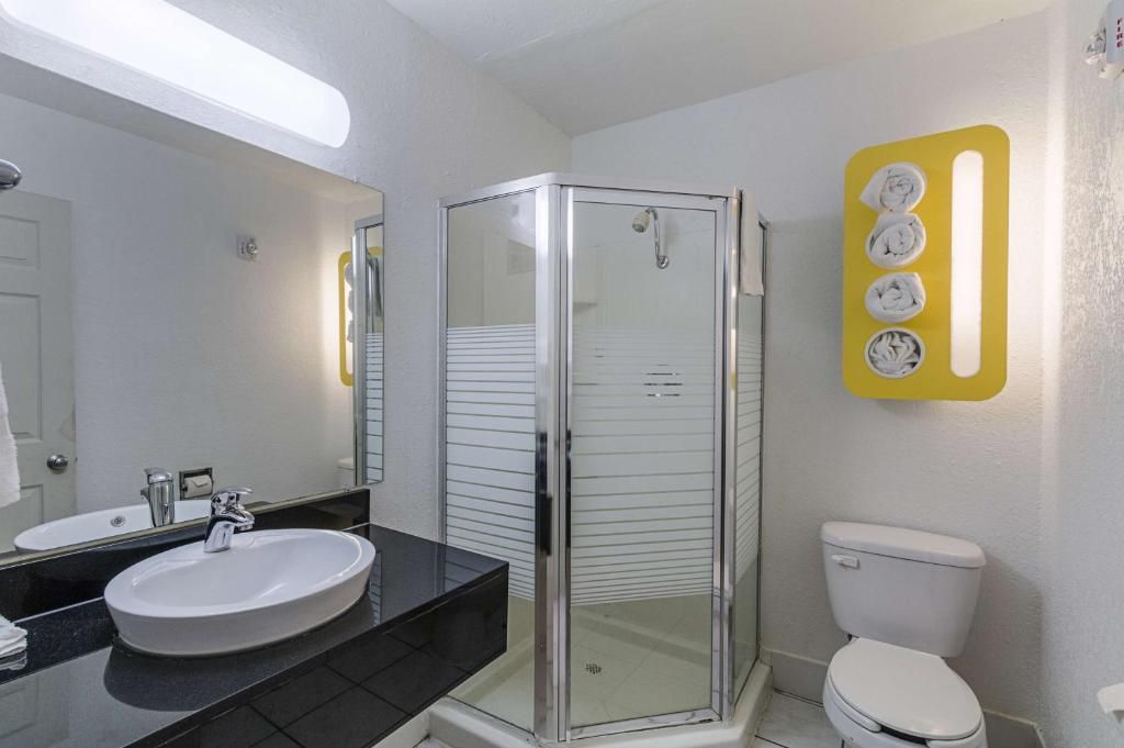 Een badkamer met een douchecabine van glas, een wit wastafelmeubel en een toilet.