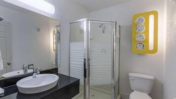Een badkamer met een douchecabine van glas, een wit wastafelmeubel en een toilet.