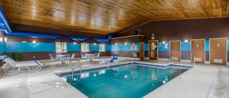 An indoor swimming pool with a wooden ceiling, blue walls, and a lifeguard chair.