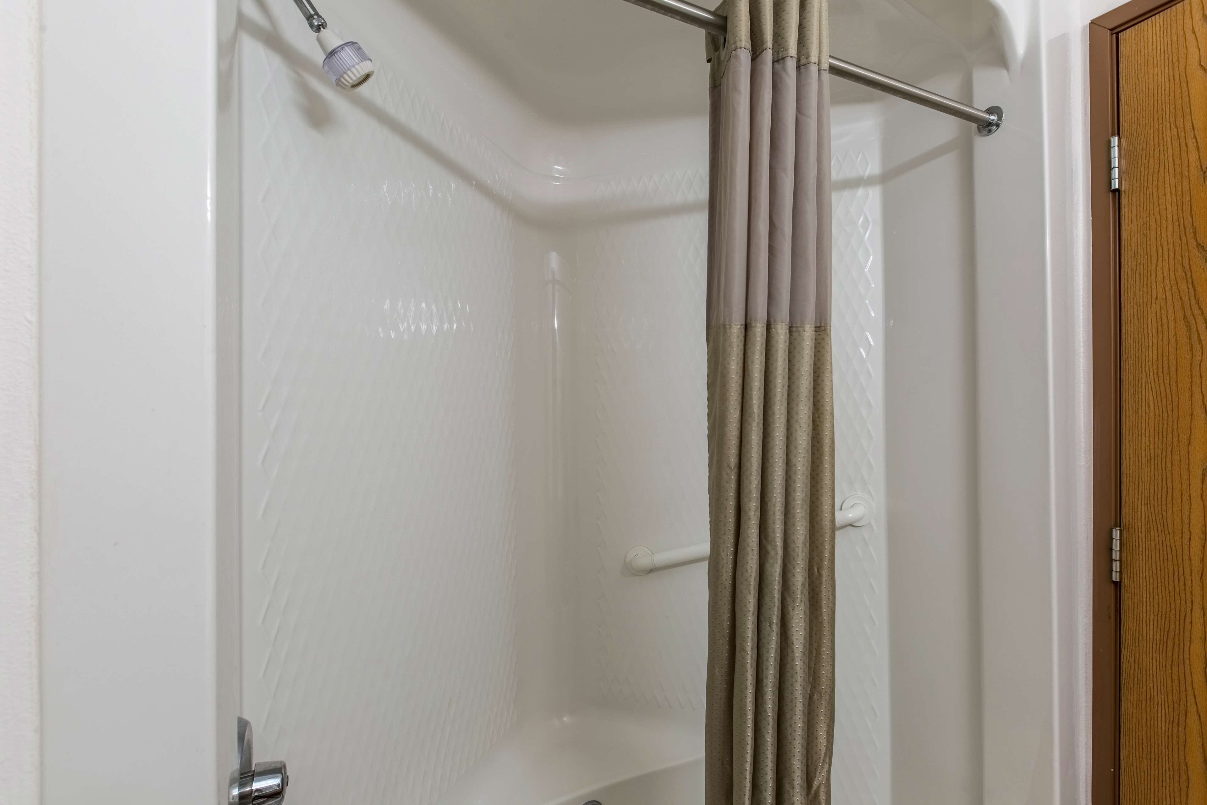A shower with a glass door, a towel rack, and a wooden door.
