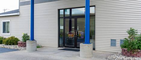 Un edificio de diseño moderno, con una amplia entrada de cristal y columnas estructurales azules.