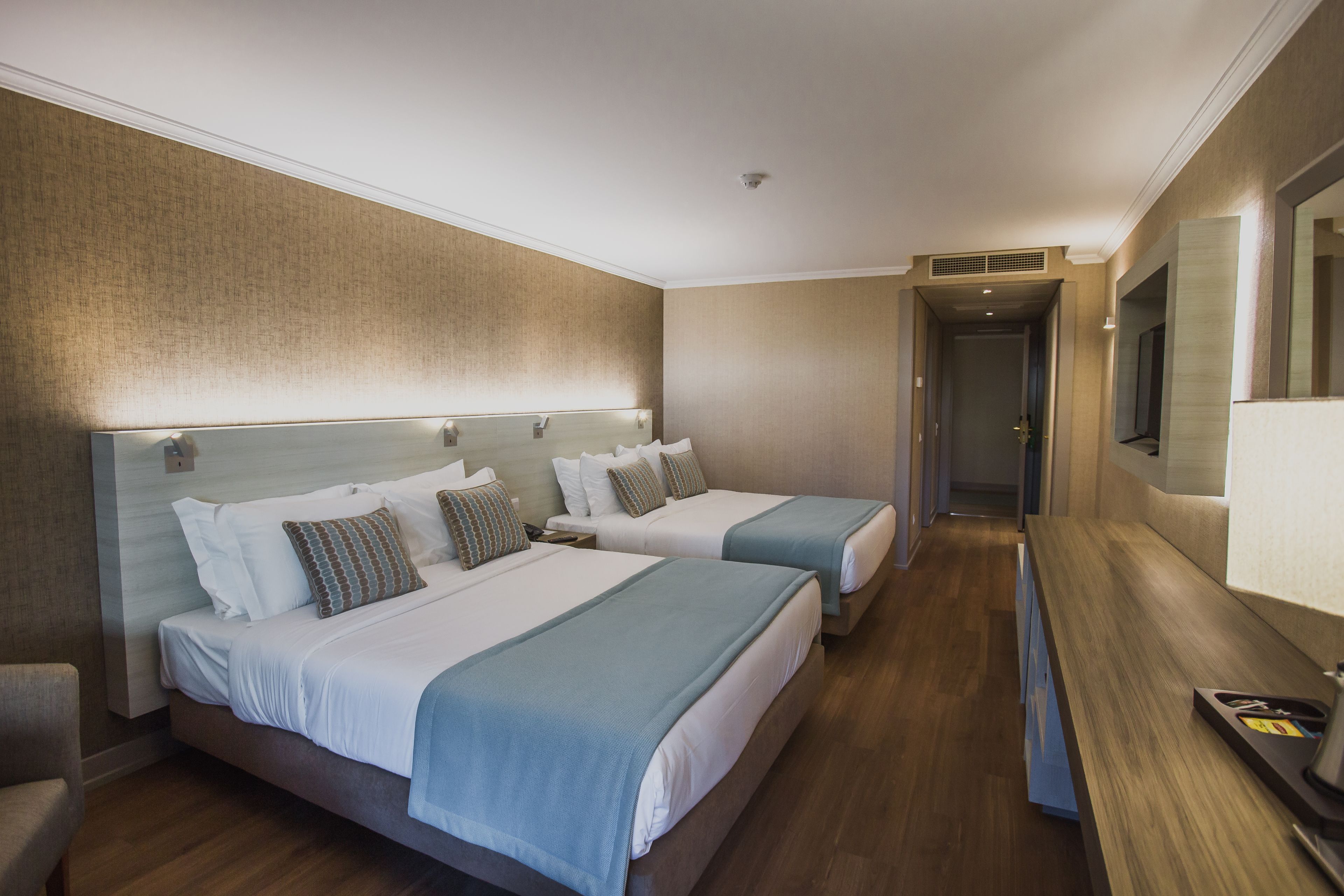 Ein Hotelzimmer mit zwei Betten, einem Schreibtisch und einem Spiegel.