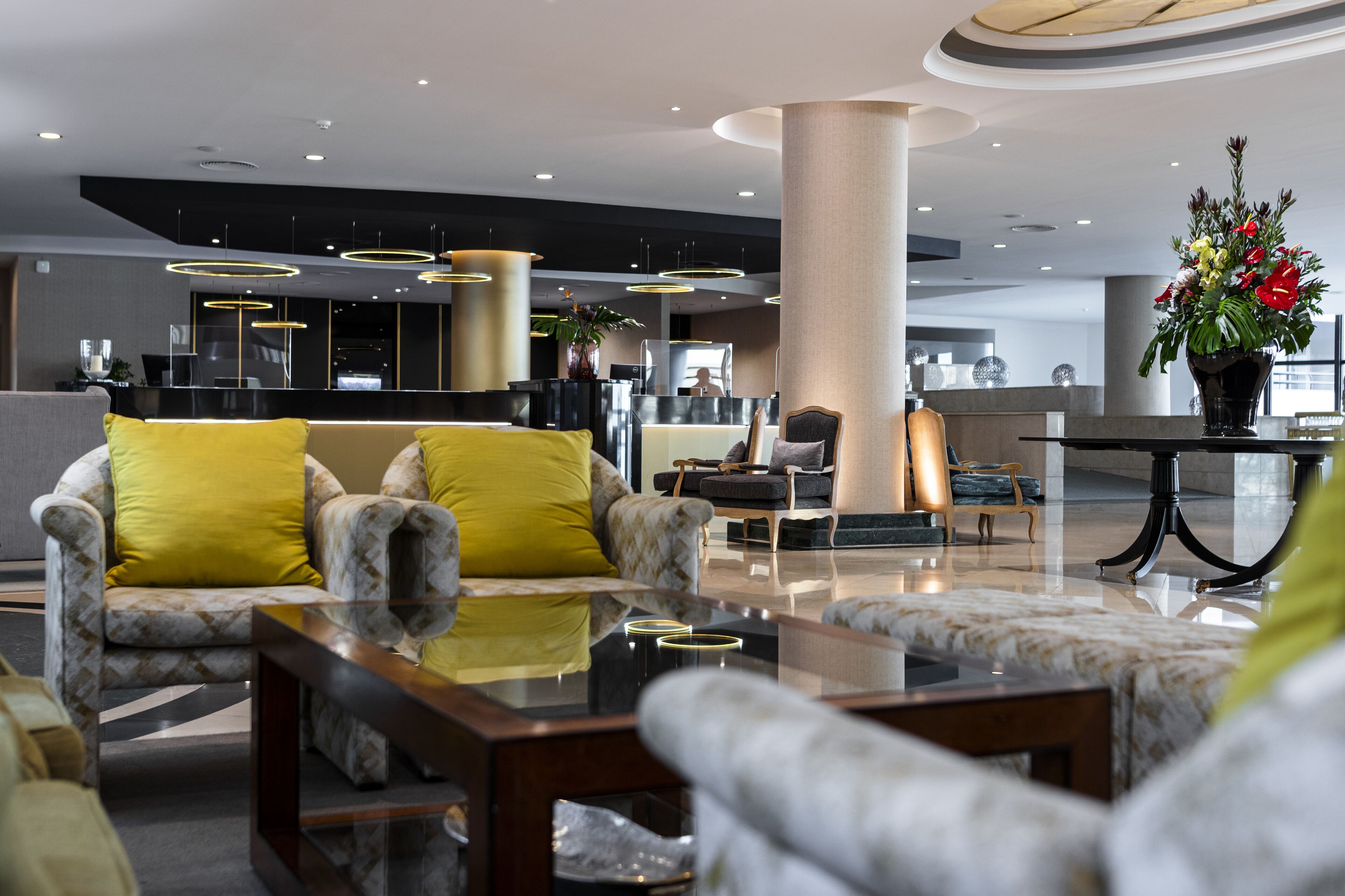 A modern lobby with a reception desk, seating area with patterned sofas, and a large decorative vase.