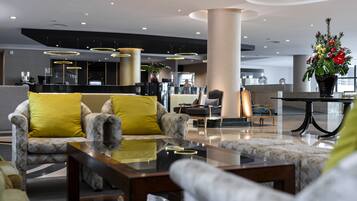 A modern lobby with a reception desk, seating area with patterned sofas, and a large decorative vase.