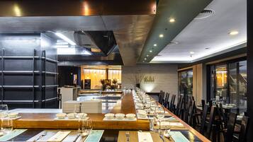 Un restaurante con una larga mesa de madera dispuesta para una comida, rodeada de sillas.