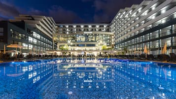 Una piscina techada, una piscina al aire libre, sombrillas