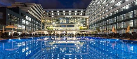 Una piscina techada, una piscina al aire libre, sombrillas