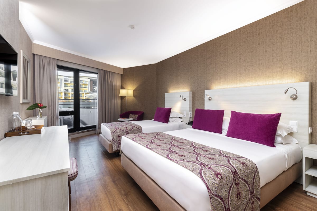 Habitación de hotel con dos camas, un escritorio y vistas a la ciudad.