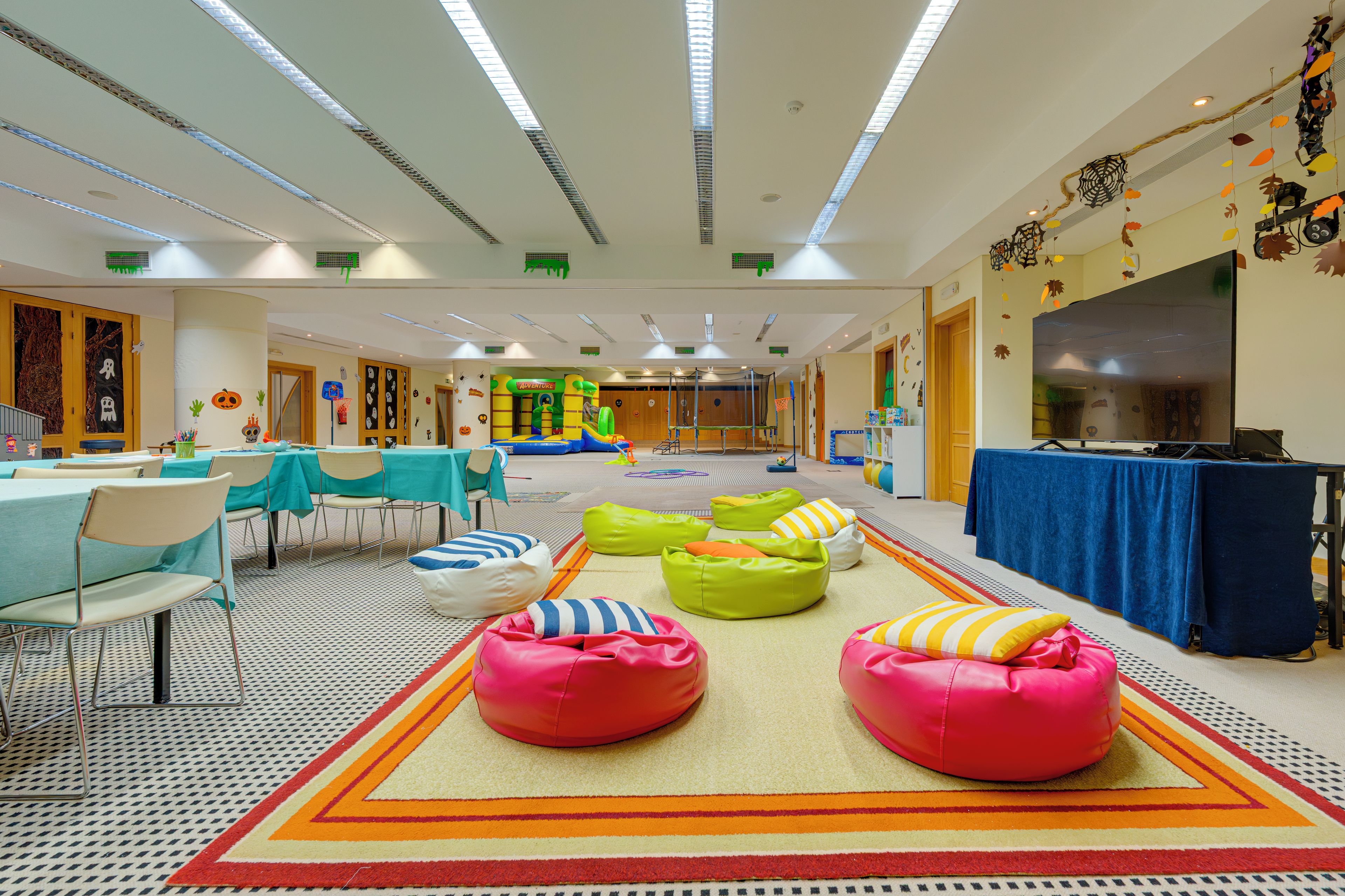 A spacious indoor area with tables, chairs, bean bags, and a play area.