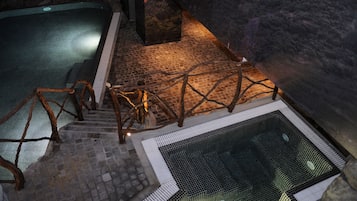 A stone staircase leading to a pool area with a wooden railing and a mesh barrier.