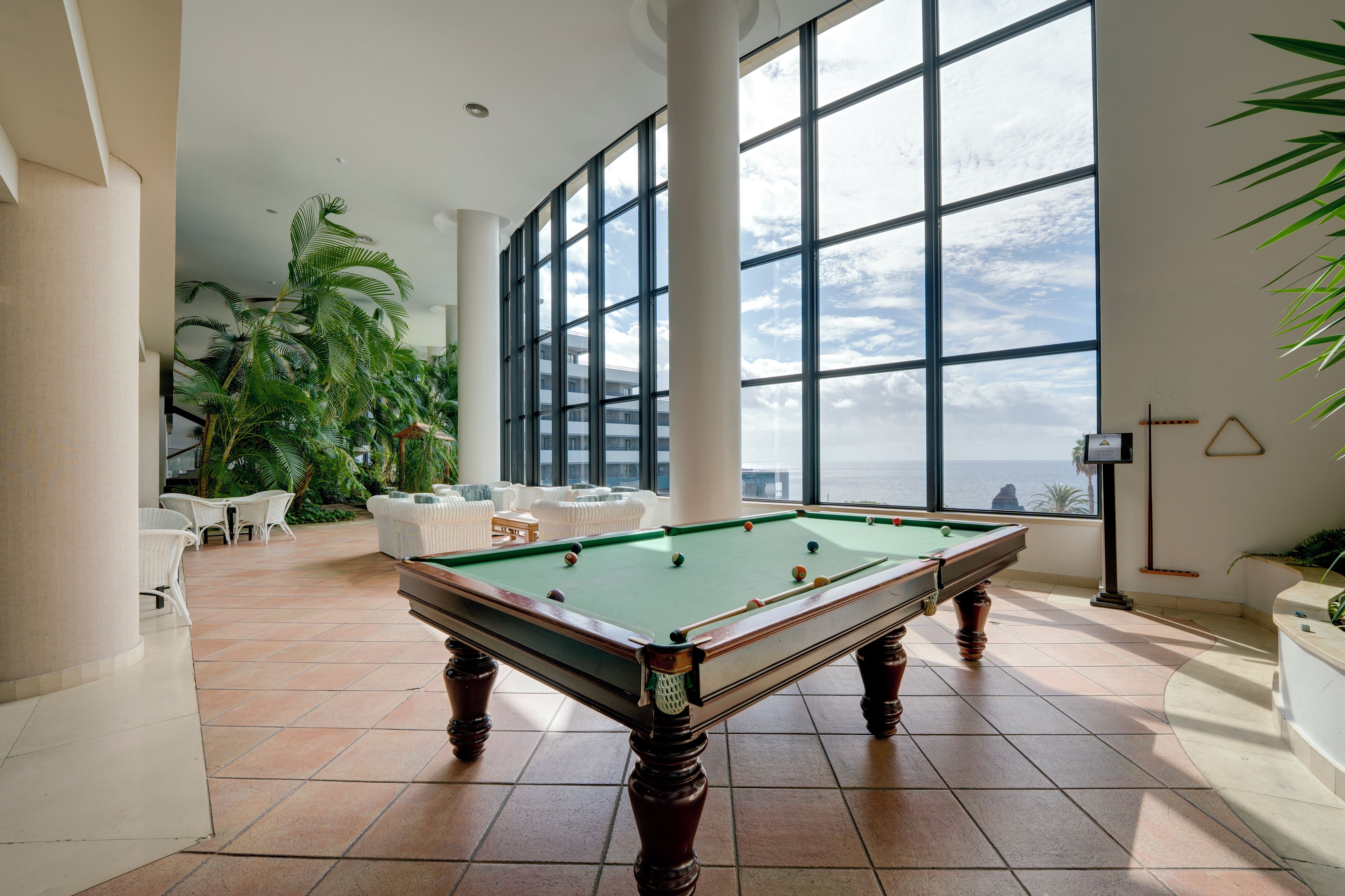 Une table de billard dans une pièce spacieuse, dotée de grandes fenêtres et offrant une vue sur la mer.