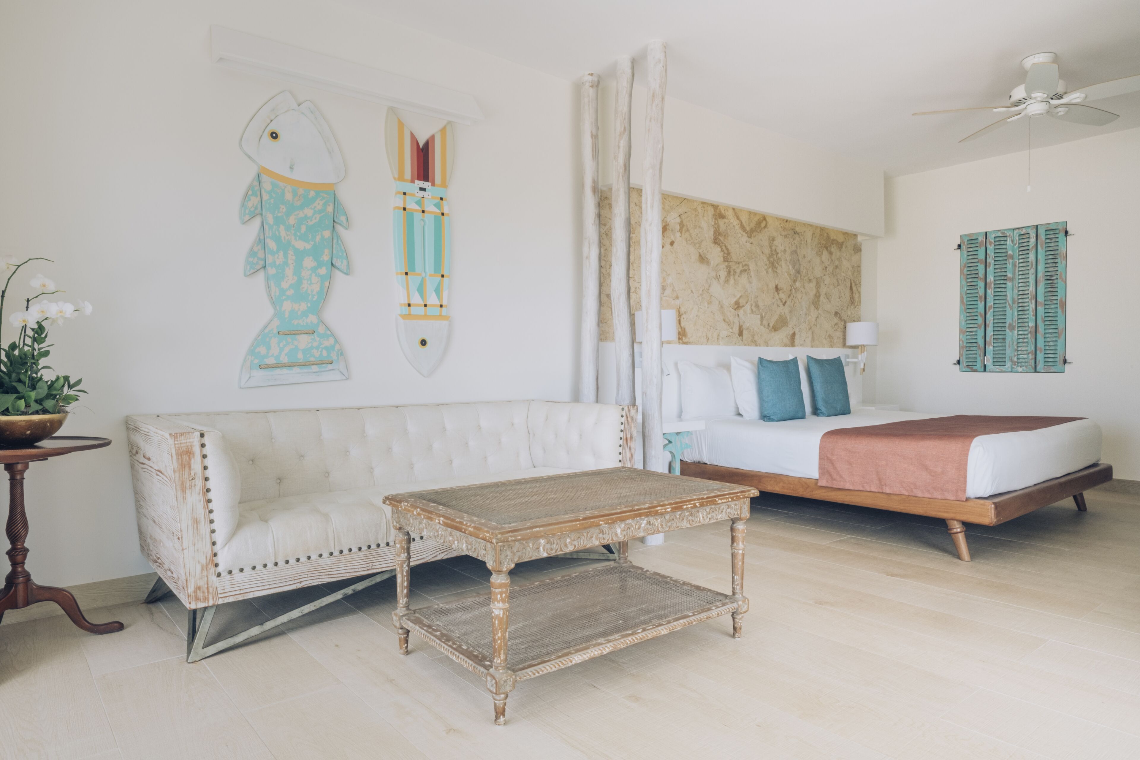 Ein Schlafzimmer mit einem Bett, einem weißen Sofa, einem Holztisch und einer Wanddekoration mit Fischen.