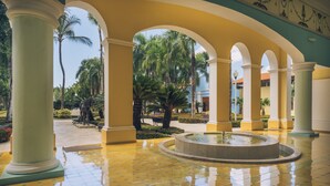 A spacious courtyard with a fountain, palm trees, and a tiled floor. - Iberostar Selection Hacienda Dominicus - All Inclusive (San Rafael del Yuma)