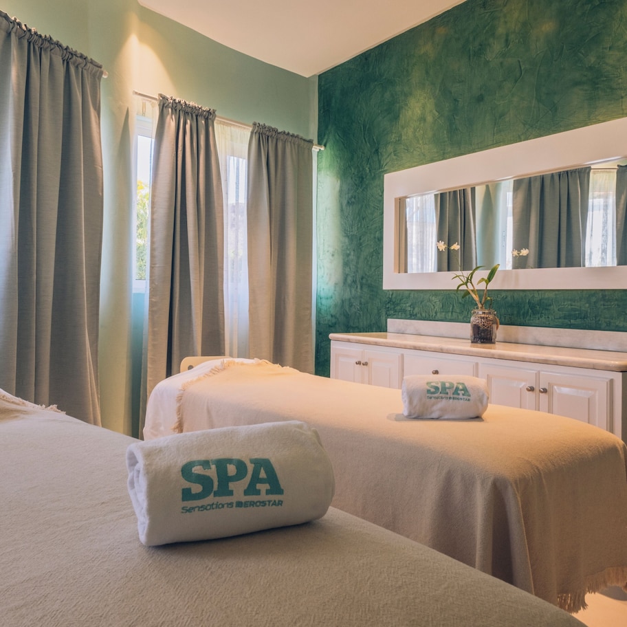 A spa room with two beds, a mirror, a vanity, and a chair.