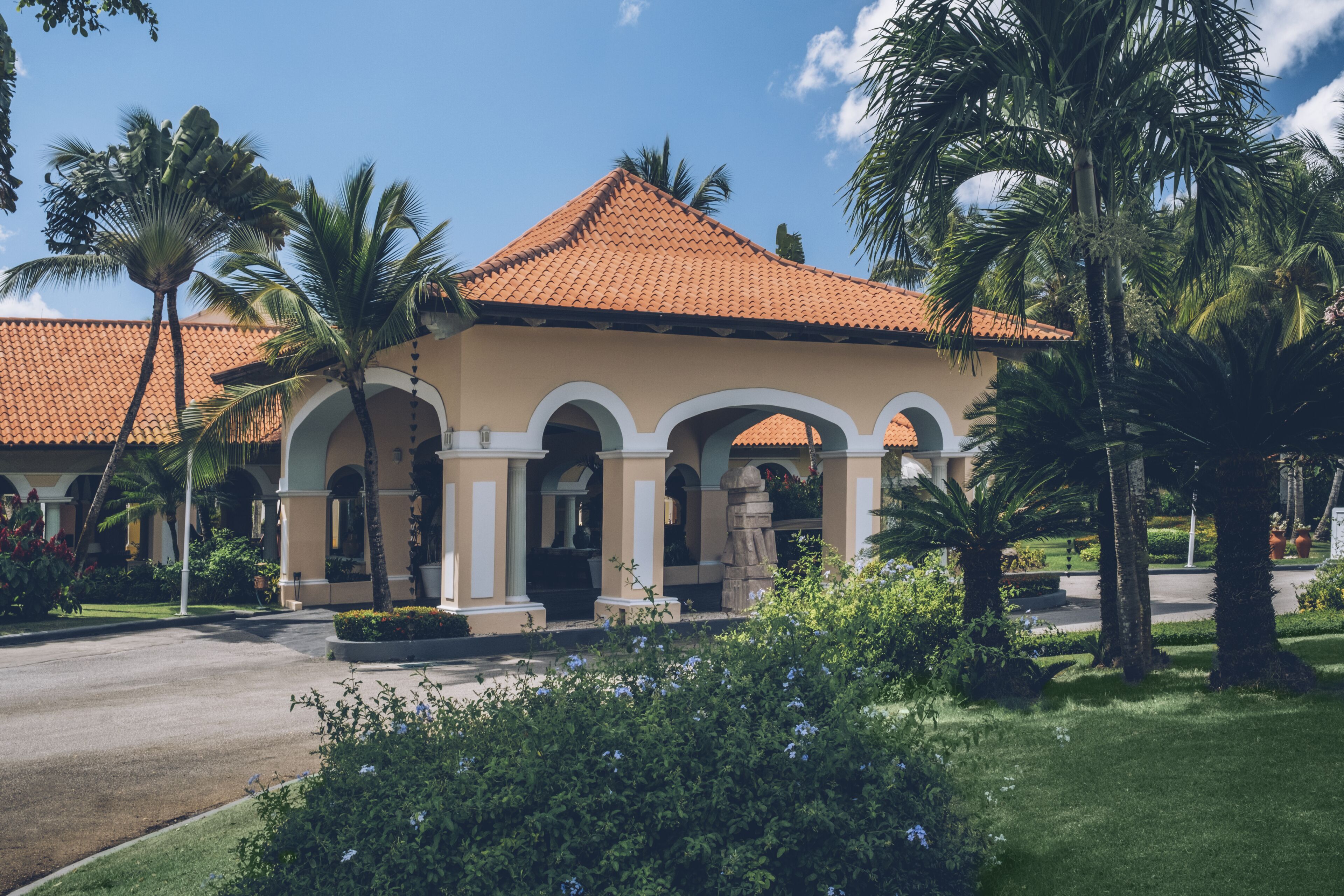 A building with a tiled roof, arched entrance, and palm trees.