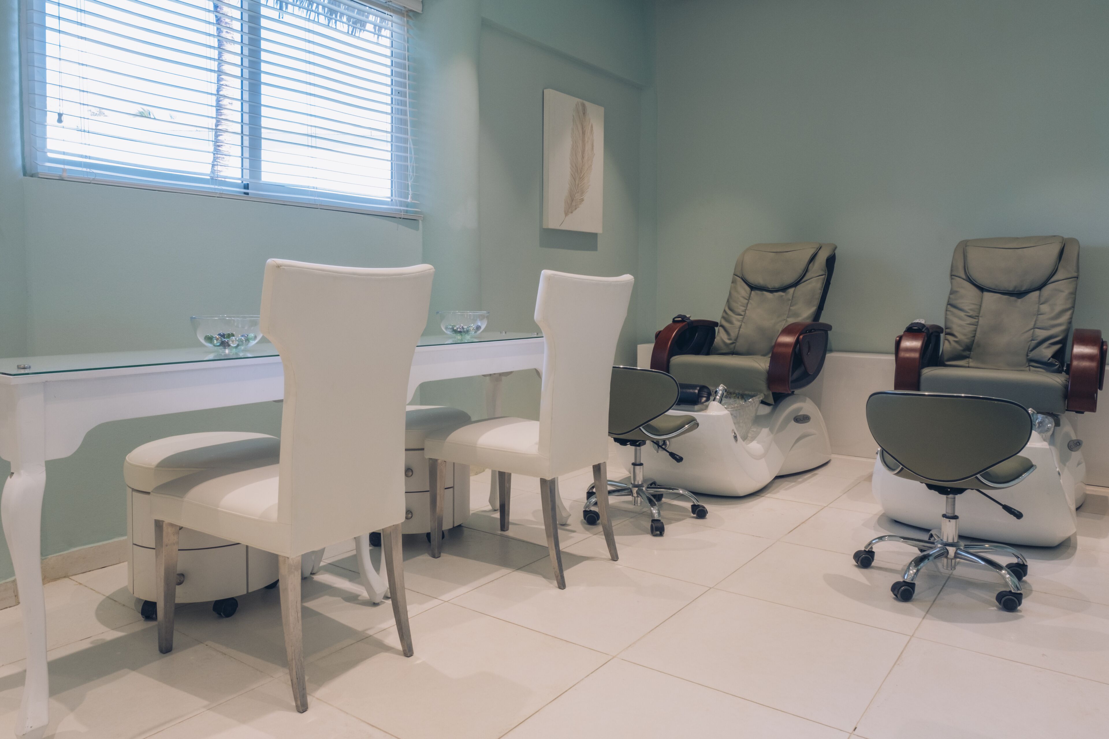 A dental clinic with white chairs, a reception desk, and a large window with blinds.