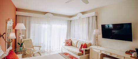 A hotel room with a bed, a desk, a television, and a ceiling fan.