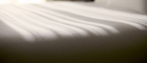 A close-up of a bed with a textured white cover.