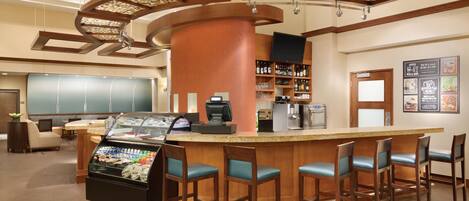 A bar area with a counter, seating, and a beverage display.