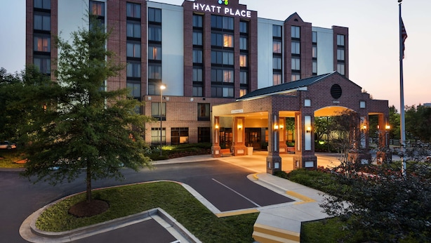 A multi-story hotel with a prominent entrance, a landscaped driveway, and a flagpole. - Hyatt Place Raleigh-Durham Airport (Morrisville)