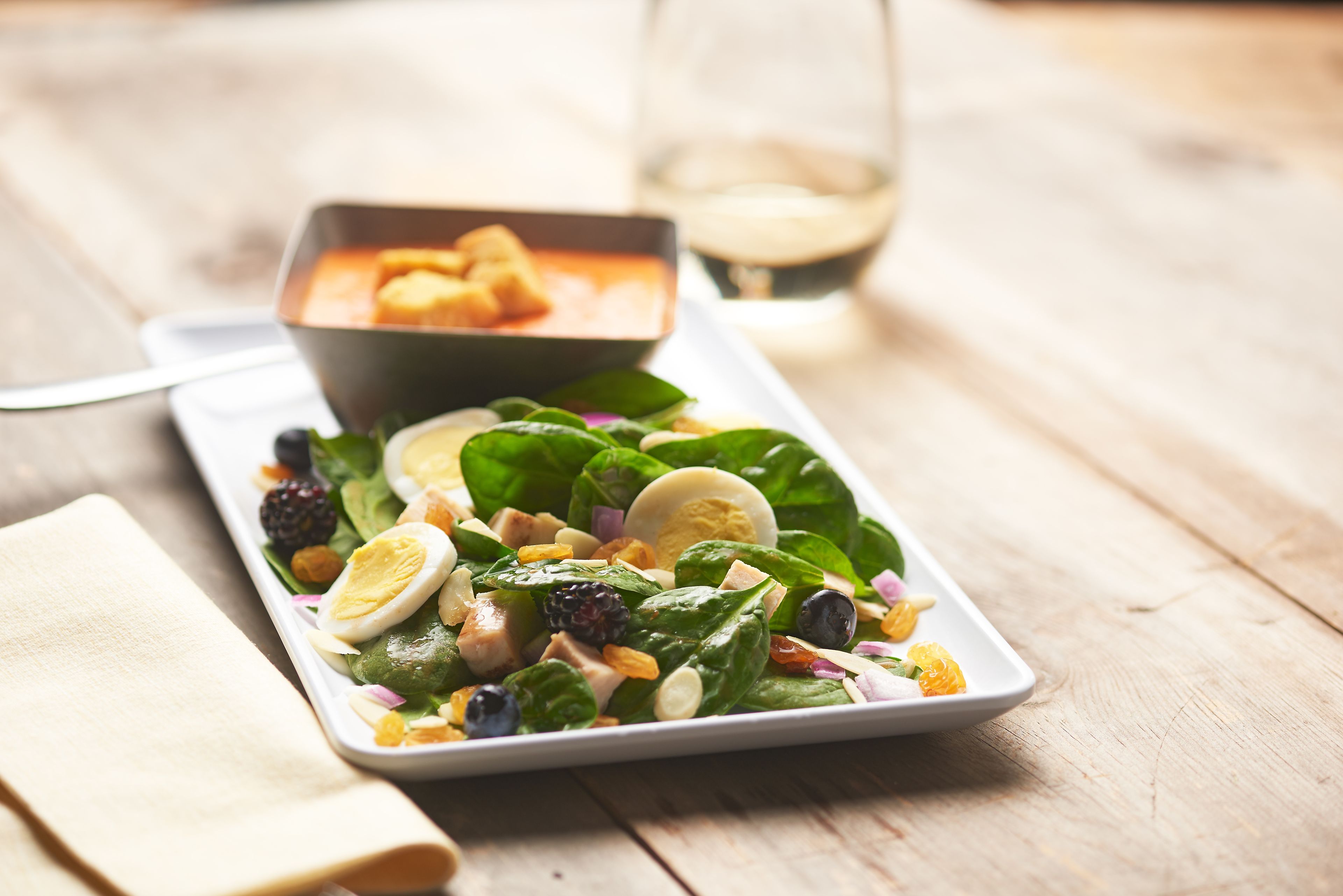 Une salade composée de légumes verts, d’œufs et de baies, servie dans une assiette blanche.
