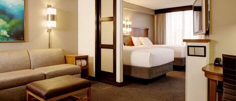 A hotel room with a sofa, a bed, a desk, and a TV.