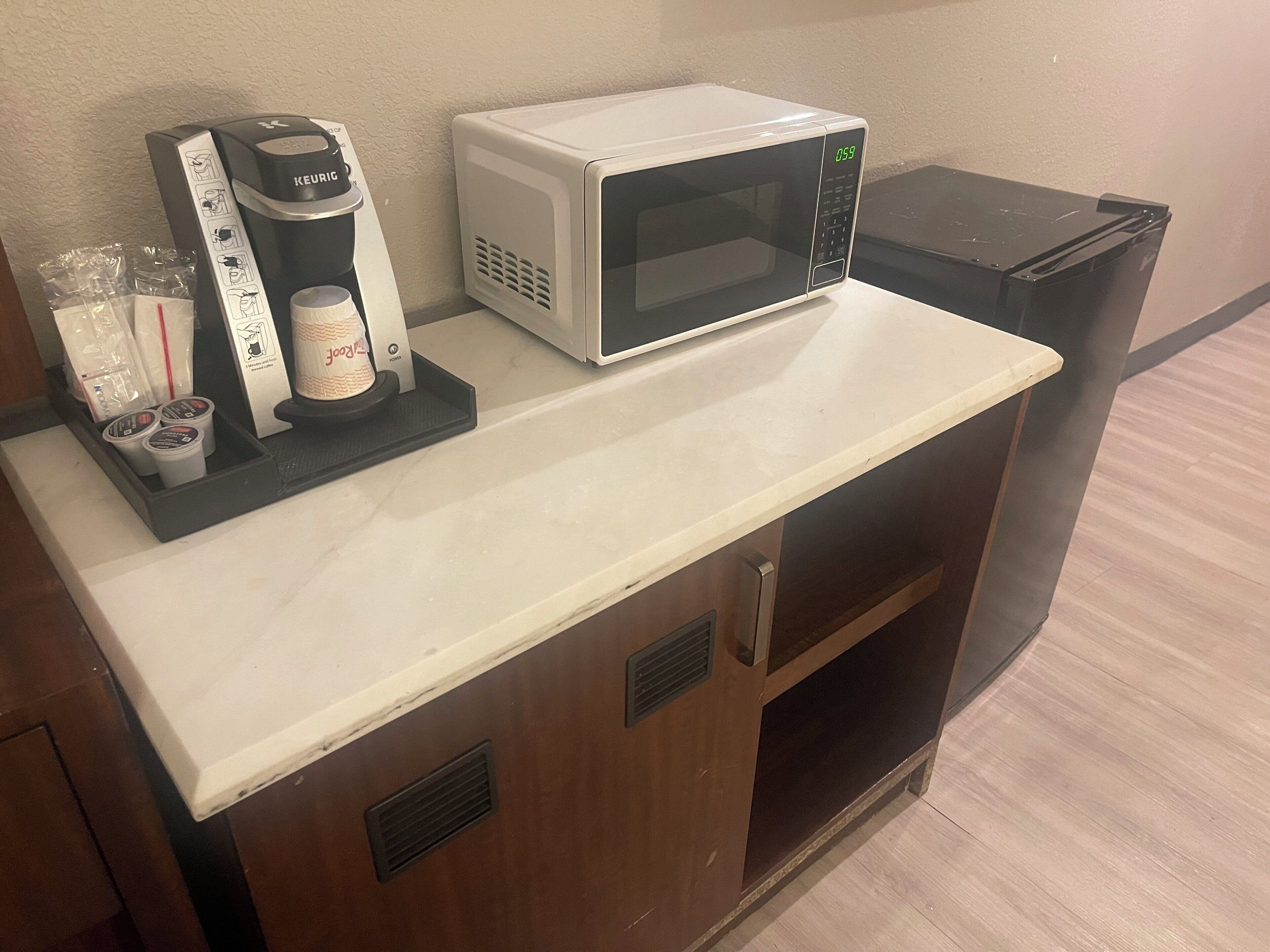 A kitchenette with a coffee maker, microwave, and small refrigerator.