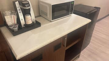 A kitchenette with a coffee maker, microwave, and small refrigerator.