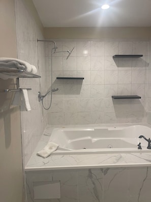 A modern bathroom with a large bathtub, towel racks, and built-in shelves. - Red Roof Inn & Suites Hinesville (Hinesville)