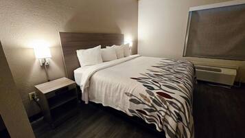 A hotel room with a bed, bedside table, lamp, and a large window.