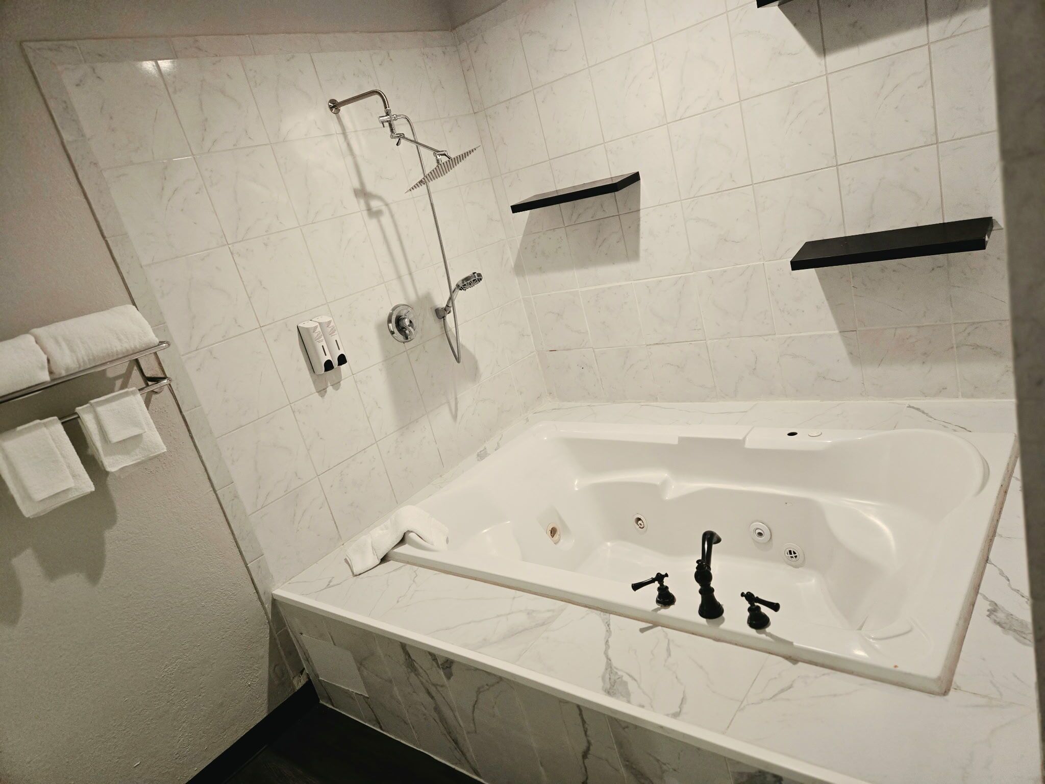 A modern bathroom with a large bathtub, a shower, and a towel rack.