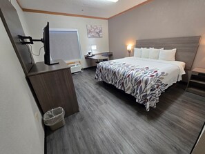 Habitación de hotel con cama, escritorio, silla y televisor.