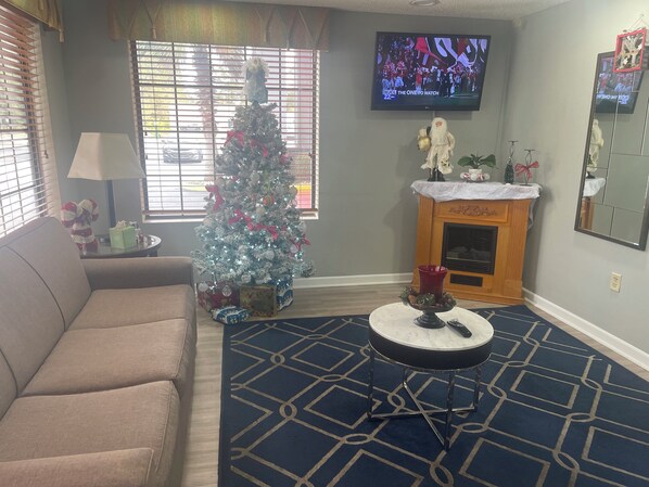 Una sala de estar con un árbol de Navidad, una chimenea, un televisor y un sofá.