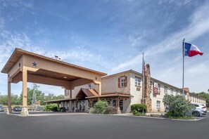 Un hotel con una bandera tejana, un espacio al aire libre cubierto y un molino.