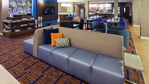 A hotel lobby with a seating area, a bar, and a television screen. - Courtyard by Marriott Boulder Longmont (Longmont)
