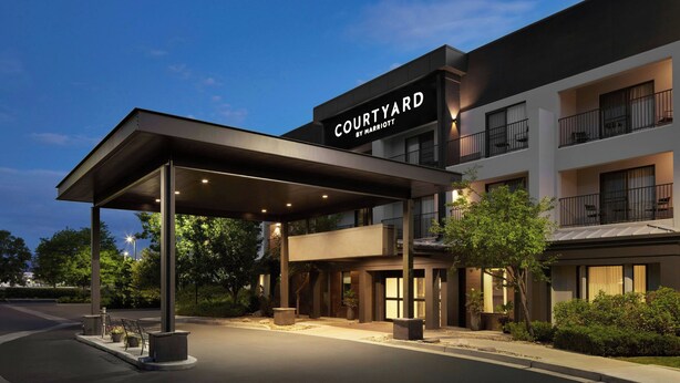A modern hotel entrance with a covered driveway, outdoor seating, and a sign reading "COURTYARD BY MARRIOTT". - Courtyard by Marriott Boulder Longmont (Longmont)