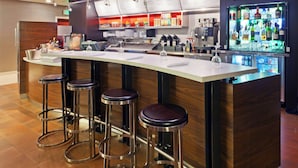 A modern bar area with a long counter, stools, and a refrigerated bar display. - Courtyard by Marriott Boulder Longmont (Longmont)