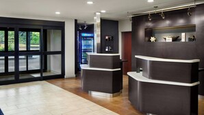 A reception area with a dark reception desk, a glass door entrance, and a Pepsi refrigerator. - Courtyard by Marriott Boulder Longmont (Longmont)
