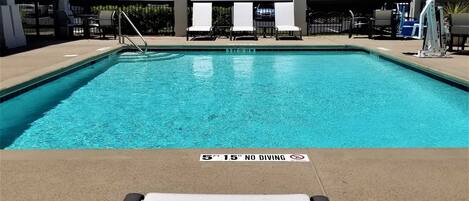 A swimming pool with lounge chairs and a no diving sign.