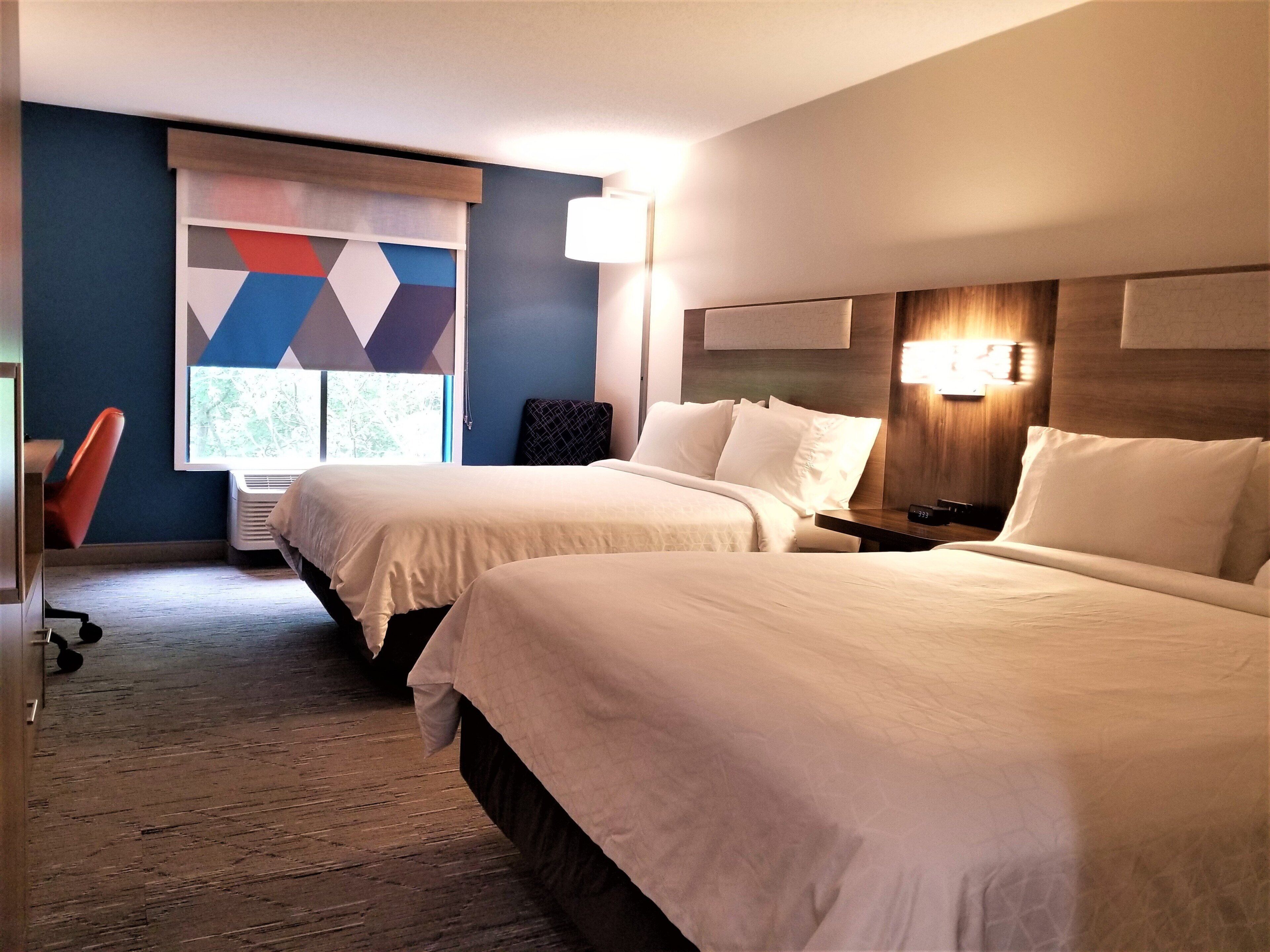 A hotel room with two beds, a desk, and a chair.