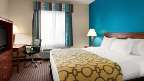 Een hotelkamer met een bed, een bureau met stoel, een televisie en een raam met gordijnen.